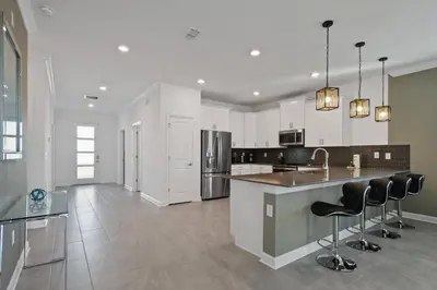 a kitchen with white cabinets and a counter with bar stools at Spacious 9BR w Pool Theater at Storey Lake in Kissimmee