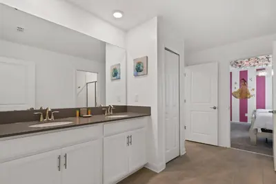 a white bathroom with two sinks and a mirror at Spacious 9BR w Pool Theater at Storey Lake in Kissimmee
