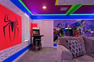 a room with a couch and a wall with superhero cartoons at Spacious 9BR w Pool Theater at Storey Lake in Kissimmee