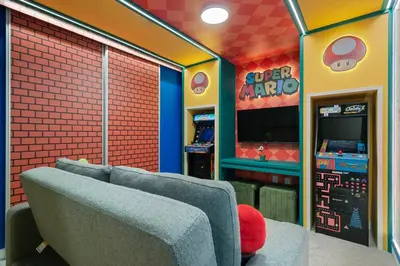 a room with a video game arcade with a couch at 3BR Home w Game Room Near Disney in Kissimmee