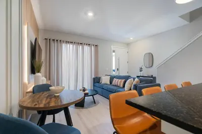 a living room with a blue couch and a table at 3BR Home w Game Room Near Disney in Kissimmee