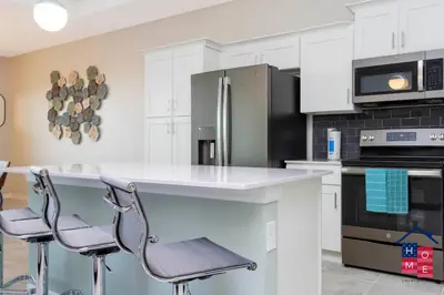 a kitchen with white cabinets and a counter with stools at Luxury Condo Near Disney and Resort Access in Kissimmee