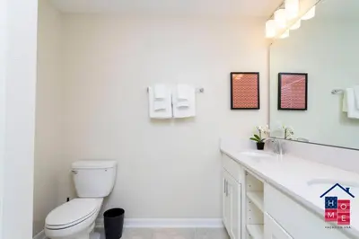 a white bathroom with a toilet and a sink at Lake View Condo with Resort in Kissimmee