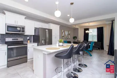 a kitchen with white cabinets and a kitchen island with bar stools at Vibrant Family Condo -10 Min From Disney in Kissimmee