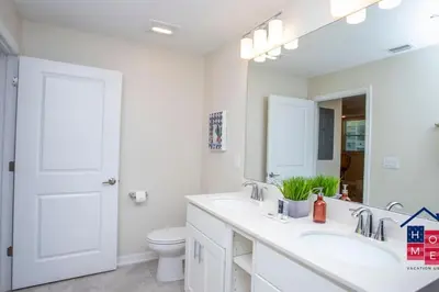 a bathroom with two sinks and a toilet and a mirror at Stunning Condo in the Heart of Orlando in Kissimmee