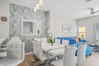 a living room with a dining table and a blue couch at Elegant Townhome with Water View in Kissimmee