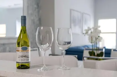 a bottle of wine and two wine glasses on a table at Elegant Townhome with Water View in Kissimmee