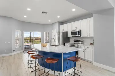 a kitchen with white cabinets and a blue island with stools at Windsor Hills View in Orlando
