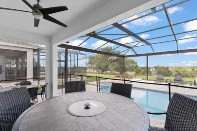 a patio with a table and chairs and a pool at Windsor Hills View in Orlando