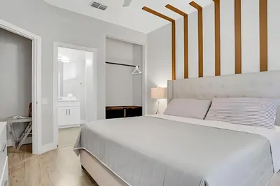 a white bedroom with a large bed with striped walls at Luxo 5Q Windsor Hills c/ Piscina e Game Room in Orlando