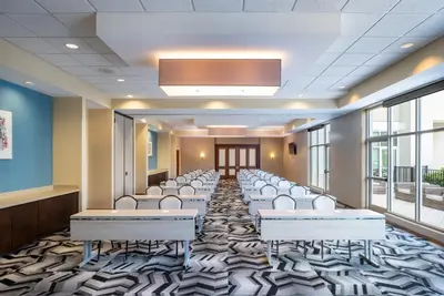 a conference room with white chairs and desks and windows at TownePlace Suites Orlando at FLAMINGO CROSSINGS Town Center, Western Entrance in Orlando
