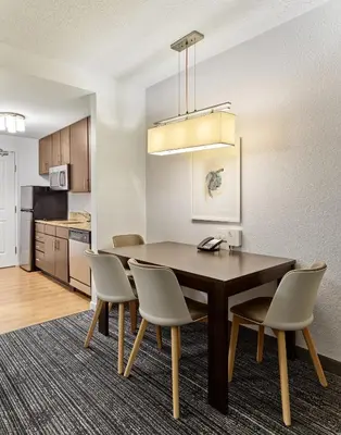 a kitchen and dining room with a table and chairs at TownePlace Suites Orlando at FLAMINGO CROSSINGS Town Center, Western Entrance in Orlando