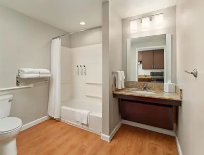 a bathroom with a tub and a toilet and a sink at TownePlace Suites Orlando at FLAMINGO CROSSINGS Town Center, Western Entrance in Orlando