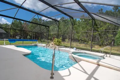 a swimming pool with a glass enclosure in a backyard at Free pool-spa heat - Near Disney - Nature view in Orlando