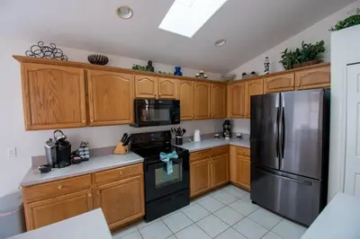 a kitchen with wooden cabinets and a stainless steel refrigerator at Free pool-spa heat - Near Disney - Nature view in Orlando