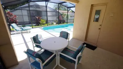 a table and chairs next to a swimming pool at Rocco's Retreat in Orlando
