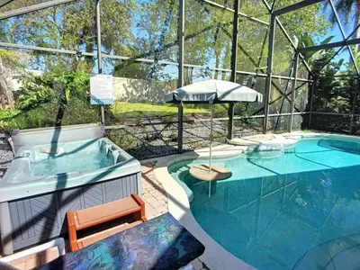 a swimming pool with a hot tub and an umbrella at Pool Paradise in Orlando