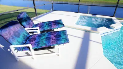 a chair and a table next to a swimming pool at Minnie's Marvel in Kissimmee