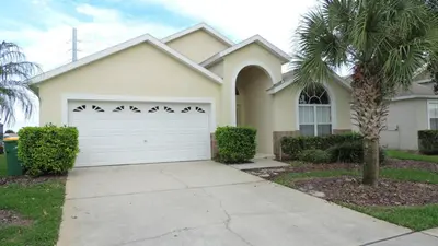 a house with a white garage door and a palm tree at Minnie's Marvel in Kissimmee