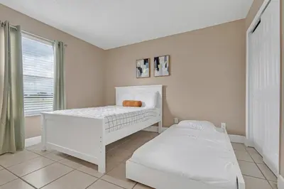 a white bedroom with a bed and a window at Lakefront Home with Game Room and Views in Kissimmee