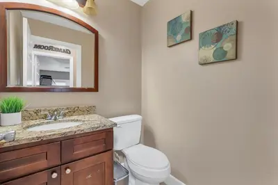 a bathroom with a toilet and a sink and a mirror at Lakefront Home with Game Room and Views in Kissimmee