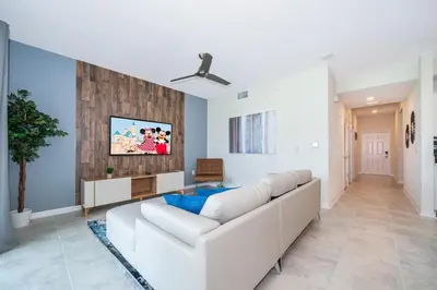 a living room with a white couch and a tv at Condo in the Heart of Orlando - 10 Min from Disney in Kissimmee