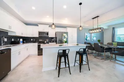 a kitchen with white cabinets and a bar with stools at Condo in the Heart of Orlando - 10 Min from Disney in Kissimmee
