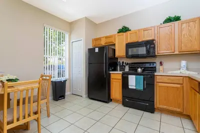 a kitchen with black appliances and wooden cabinets at Central House Near Disney in Orlando