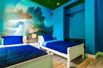 a blue bedroom with two beds and a painting at Casa 4Q Windsor Hills c/ Piscina e Game Room in Orlando