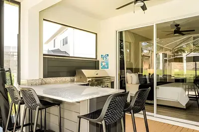 a kitchen with a bar with chairs and a bedroom at Casa 4Q Windsor Hills c/ Piscina e Game Room in Orlando