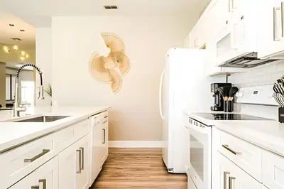 a kitchen with white cabinets and a refrigerator at Casa 4Q Windsor Hills c/ Piscina e Game Room in Orlando