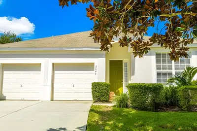 a white house with two garage doors at Casa 4Q Windsor Hills c/ Piscina e Game Room in Orlando