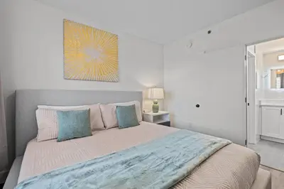a white bedroom with a large bed with blue pillows at King suite near Epic & Universal, free parking in Orlando
