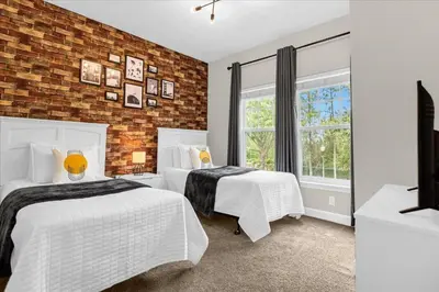 a bedroom with two beds and a brick wall at Casa 4Q c/ Piscina e Padaria – Perto da Disney in Kissimmee