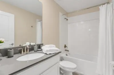 a white bathroom with a sink and a toilet at Huge 9-Bedroom Luxury Villa Near Disney With Pool in Kissimmee