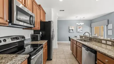 a kitchen with stainless steel appliances and wooden cabinets at Family Resort Getaway w Pool & Patio near Disney in Kissimmee