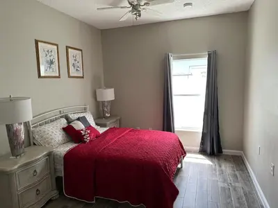 a bedroom with a bed with a red blanket and a window at Orlando Lakefront Pool Villa 25 min Disney & Univ in Orlando