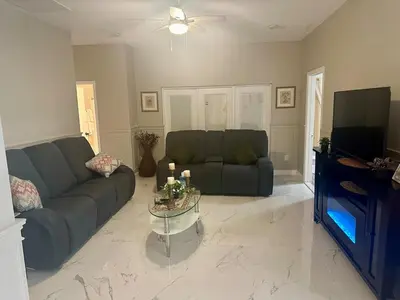 a living room with a couch and a table and a tv at Orlando Lakefront Pool Villa 25 min Disney & Univ in Orlando