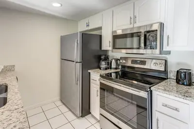 a kitchen with white cabinets and a stainless steel refrigerator at Gateway to Orlando Theme Parks! Home with Large Yard in Orlando