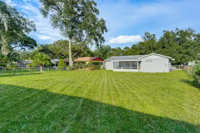 a large yard with a white house in the background at Gateway to Orlando Theme Parks! Home with Large Yard in Orlando