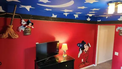 a bedroom with a red wall with a mickey mouse ceiling at Mickeys Magical Escape in Orlando