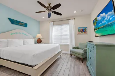 a bedroom with a bed with a ceiling fan and a chair at A Parrot's Live For Me Cottage With Private Pool Near Disney With Margaritaville Resort & Island H20 Waterpark Access - 8028Sh in Orlando