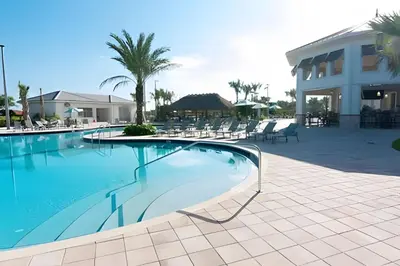 a swimming pool with chairs and a building at Casa 5Q c/ Piscina Sul e Game Room – Storey Lake in Kissimmee