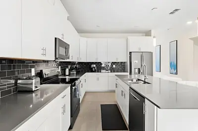 a large kitchen with white cabinets and black appliances at Casa 6Q c/ Piscina & Quartos Temáticos in Kissimmee