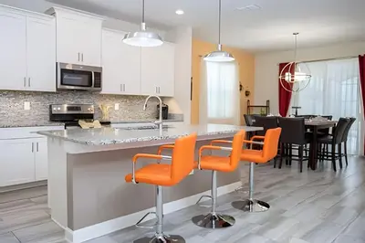 a kitchen and dining room with orange chairs at a counter at Casa 6Q c/ Piscina – 10 Min da Disney in Kissimmee