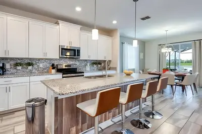 a kitchen with white cabinets and a island with chairs at Casa 6Q c/ Piscina + Temas Disney – Storey Lake in Kissimmee