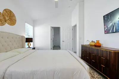 a white bedroom with a large bed and a dresser at Luxury Villa, Welcome to EDC, Pool & Spa in Orlando
