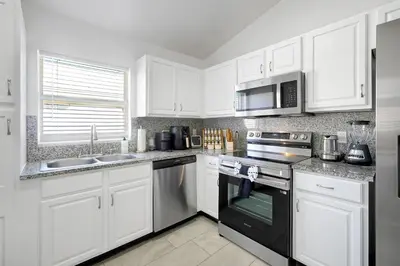 a kitchen with white cabinets and black appliances at Luxury Villa, Welcome to EDC, Pool & Spa in Orlando
