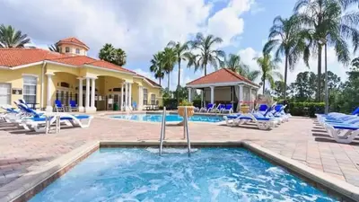 a swimming pool with chairs and a house at Disney Pixie Dust Villa in Kissimmee