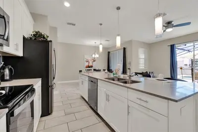 a kitchen with white cabinets and a black refrigerator at TVPM-4981WA/SL in Kissimmee